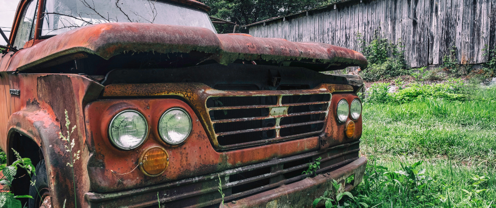 an old car parked by the grassy area